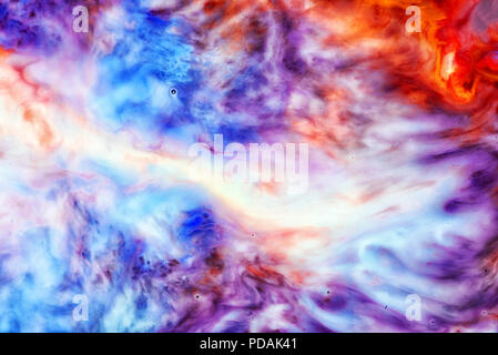 Abstract liquid milk flowing pattern like nebulae in the universe with different colours of white, blue, red and pink Stock Photo