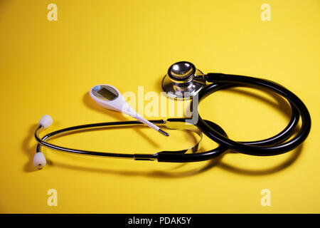 Thermometer and stethoscope isolated on a yellow background. Health care and medical instruments found at a health clinic. Stock Photo