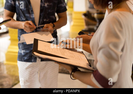 Group of tourist getting key card from hotel receptionist with a greement form in her hand. Stock Photo