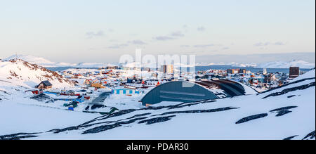 Lots of Inuit houses scattered on the hill in Nuuk city covered in snow with sea fjord and mountains in the background, Greenland Stock Photo