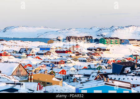 Lots of Inuit houses scattered on the hill in Nuuk city covered in snow with sea and mountains in the background, Greenland Stock Photo