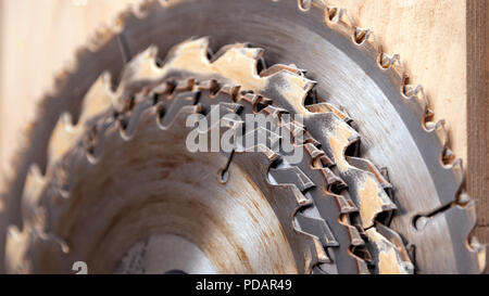Close up of a many metal circular saw blades different sizes on a wooden background in workshop Stock Photo