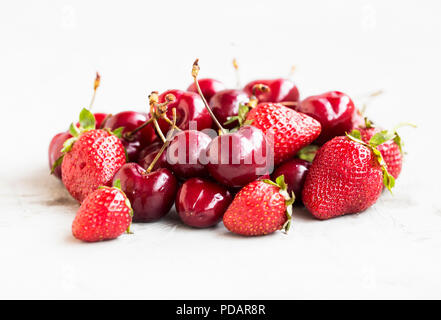 Pile of strawberries and cherries on concrete background, summer red berries Stock Photo