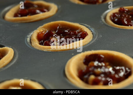 Mince pies with filling in a metal baking tray ready for topping Stock Photo