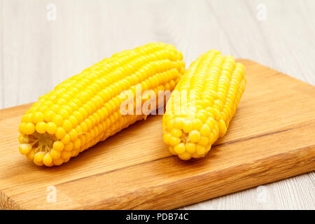 Cobs of cooked corn on cutting board with sackcloth on the background Stock Photo