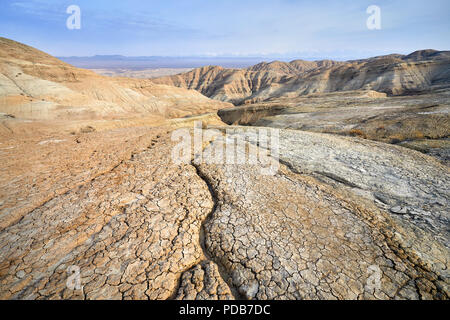 Landscape of cracked ground and mountains in the desert. National desert park Altyn Emel in Kazakhstan Stock Photo