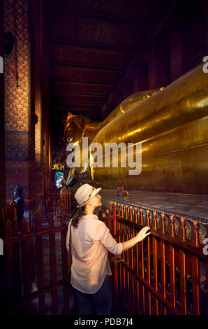 Woman tourist near Statue of Big Golden Buddha in wat Pho temple in Bangkok, Thailand. Symbol of Buddhist culture.