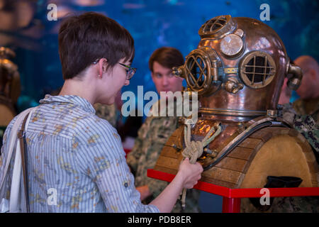 180802-N-SH284-0028 SEATTLE (August 02, 2018) A visitor at the Seattle Aquarium inspects a dive helmet at a static display presented by the Naval Station Everett dive locker during the 69th annual Seafair Fleet Week. Seafair Fleet Week is an annual celebration of the sea services wherein Sailors, Marines and Coast Guard members from visiting U.S. Navy and Coast Guard ships and ships from Canada make the city a port of call. (U.S. Navy photo by Mass Communication Specialist 2nd Class Vaughan Dill/Released) Stock Photo