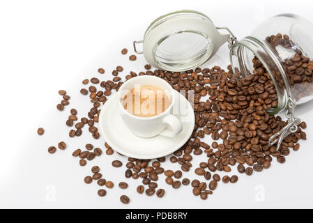 Glass food storage jar lying on side with coffee beans spilling out on white surface Stock Photo