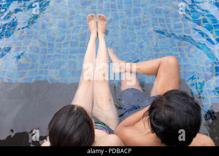 Cheerful youthful guy and lady resting while swimming pool outdoor. Couple in water Stock Photo