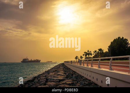 Cargo container ship leaving Dubai Marina at sunset Stock Photo