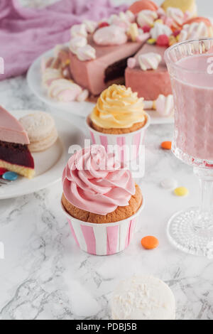 close up of birthday cupcakes, pink cake and milkshake in glass on marble table Stock Photo
