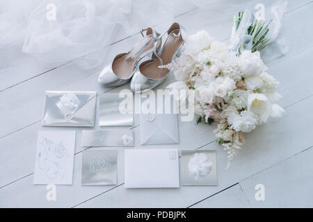 top view of stylish wedding invitations with bridal shoes and bouquet on wooden floor Stock Photo