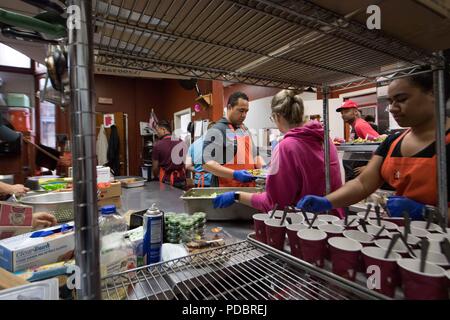 180803-N-DA737-0246 SEATTLE (Aug. 3, 2018) Hospital Corpsman 1st Class Jonathan Faletoi, (left), assigned to Naval Hospital Bremerton, prepares meals with his wife, Stephanie (middle), and sister, Patricia, (right), at Bread of Life Mission during a Seattle Seafair Fleet Week community relations event. Seafair Fleet Week is an annual celebration of the sea services wherein Sailors, Marines and Coast Guard members from visiting U.S. Navy and Coast Guard ships and ships from Canada make the city a port of call. (U.S. Navy photo by Mass Communication Specialist 2nd Class Jonathan Jiang/Released) Stock Photo