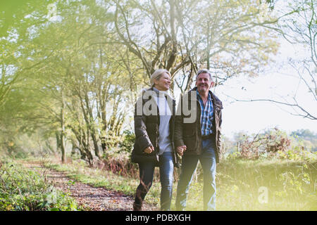 Happy mature couple holding hands, walking in autumn park Stock Photo