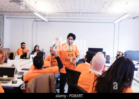 Hackers celebrating, high-fiving and coding for charity at hackathon Stock Photo