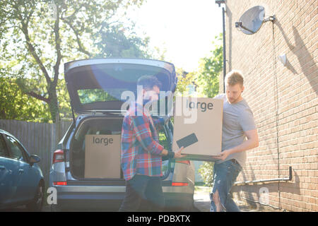 Male gay couple unloading moving boxes from car Stock Photo