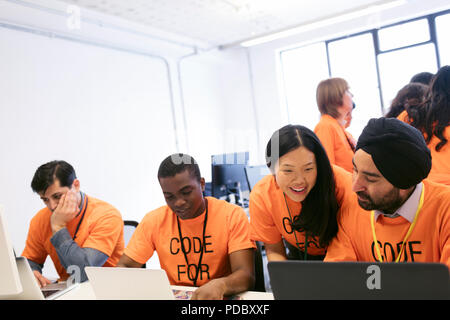 Hackers at laptops coding for charity at hackathon Stock Photo