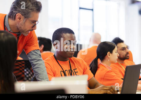 Hackers at laptops coding for charity at hackathon Stock Photo