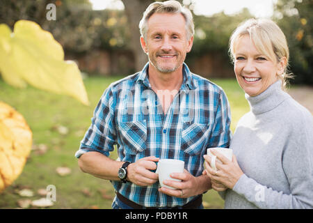 Portrait smiling, confident mature couple drinking coffee in autumn yard Stock Photo