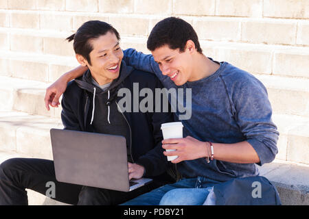 Male gay couple using laptop and drinking coffee Stock Photo