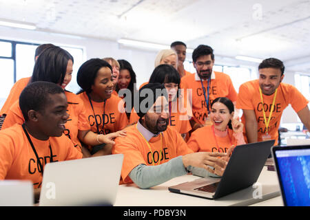 Happy hackers at laptop coding for charity at hackathon Stock Photo
