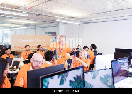 Hackers with lanyards coding for charity at hackathon Stock Photo
