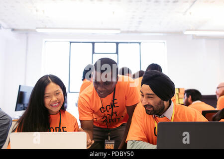 Hackers at laptops coding for charity at hackathon Stock Photo