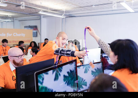Hackers with lanyard, coding for charity at hackathon Stock Photo