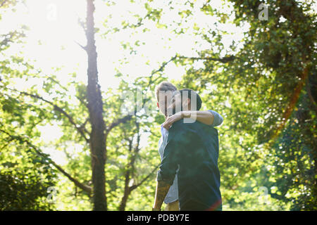 Affectionate gay couple hugging and walking in sunny park Stock Photo