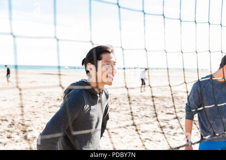 Smiling man playing beach volleyball on sunny beach Stock Photo