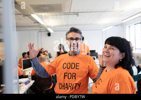 Enthusiastic hackers coding for charity at hackathon Stock Photo