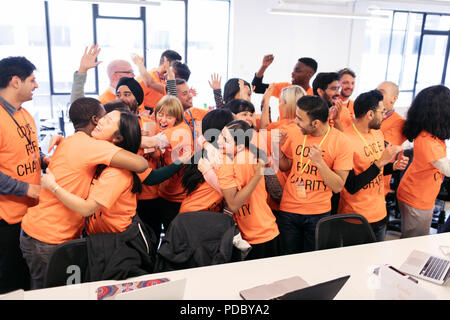 Enthusiastic hackers celebrating, coding for charity at hackathon Stock Photo