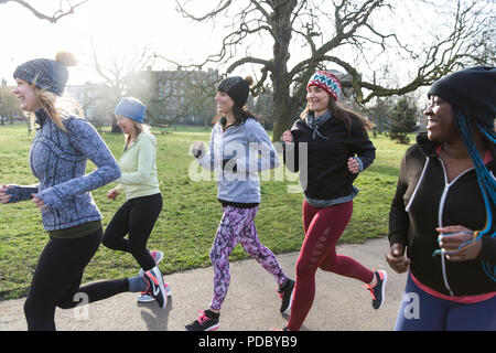 Female runners running in sunny park Stock Photo