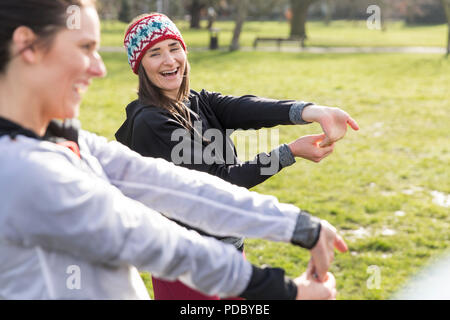 Female runners stretching wrists in park Stock Photo