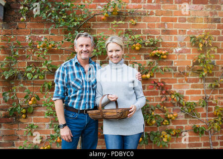 Portrait smiling mature couple harvesting apples in garden Stock Photo