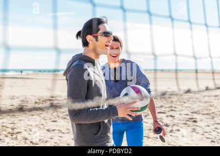 Happy male friends playing beach volleyball on sunny beach Stock Photo