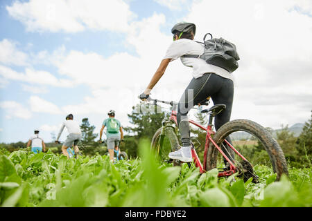 Friends mountain biking in rural field Stock Photo