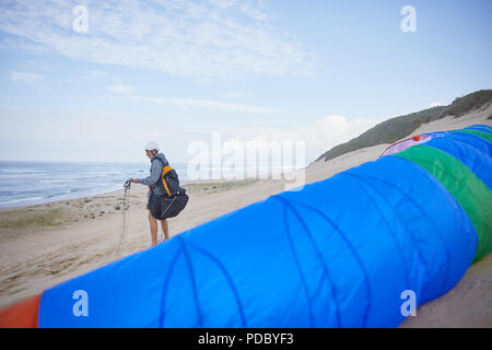 Male paraglider with parachute on ocean beach Stock Photo