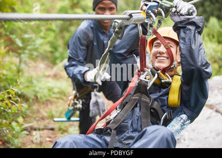 Smiling young woman zip lining Stock Photo