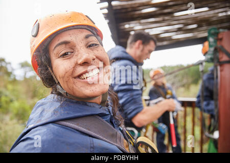 Portrait enthusiastic, muddy young woman enjoying zip lining Stock Photo