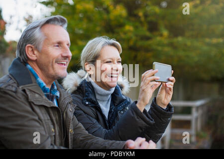 Happy mature couple using camera phone in park Stock Photo