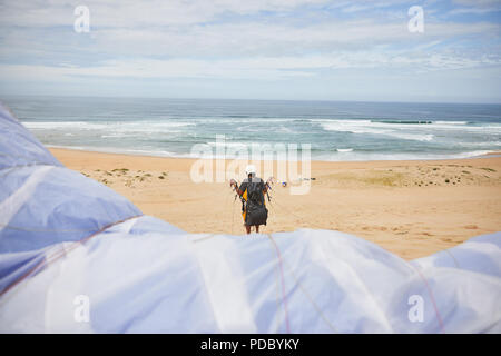 Paraglider with parachute on ocean beach Stock Photo