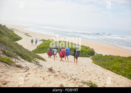 Paragliders carrying parachute backpacks on ocean beach Stock Photo