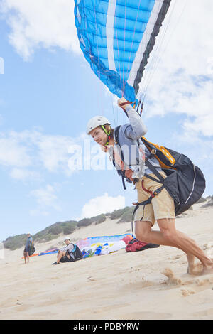 Male paraglider running on beach Stock Photo