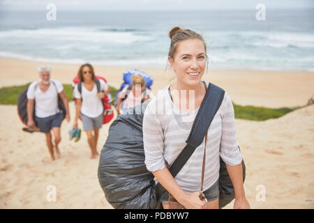 Portrait smiling, confident female paraglider carrying parachute backpack on beach Stock Photo