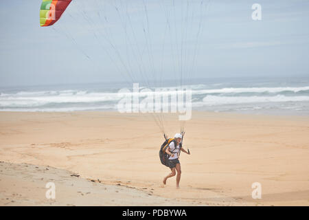 Male paraglider running on ocean beach Stock Photo