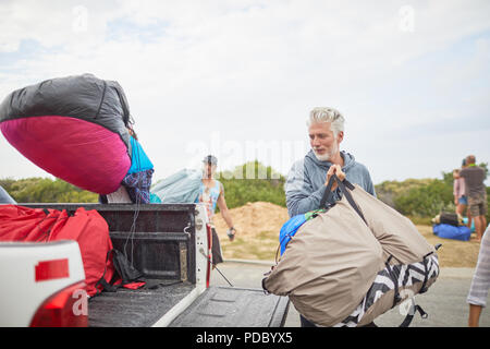 Mature male paraglider unloading parachute from truck Stock Photo