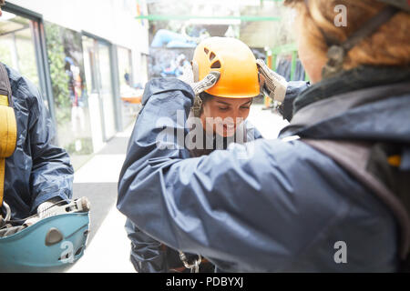 Woman helping friend with zip line helmet Stock Photo