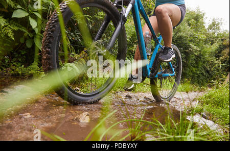 Woman mountain biking on muddy trail Stock Photo
